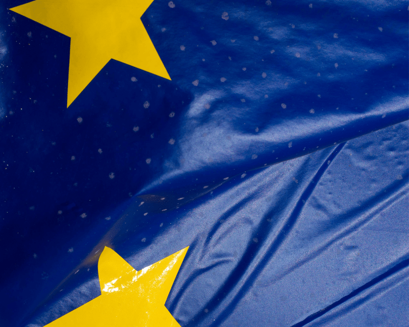 Close-up of the European Union flag showing two yellow stars on a blue background with visible creases in the fabric.