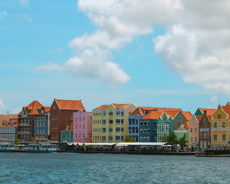 Colourful waterfront buildings in Willemstad, Curaçao, showcasing the island’s iconic Dutch colonial architecture along the harbour under a bright blue sky.
