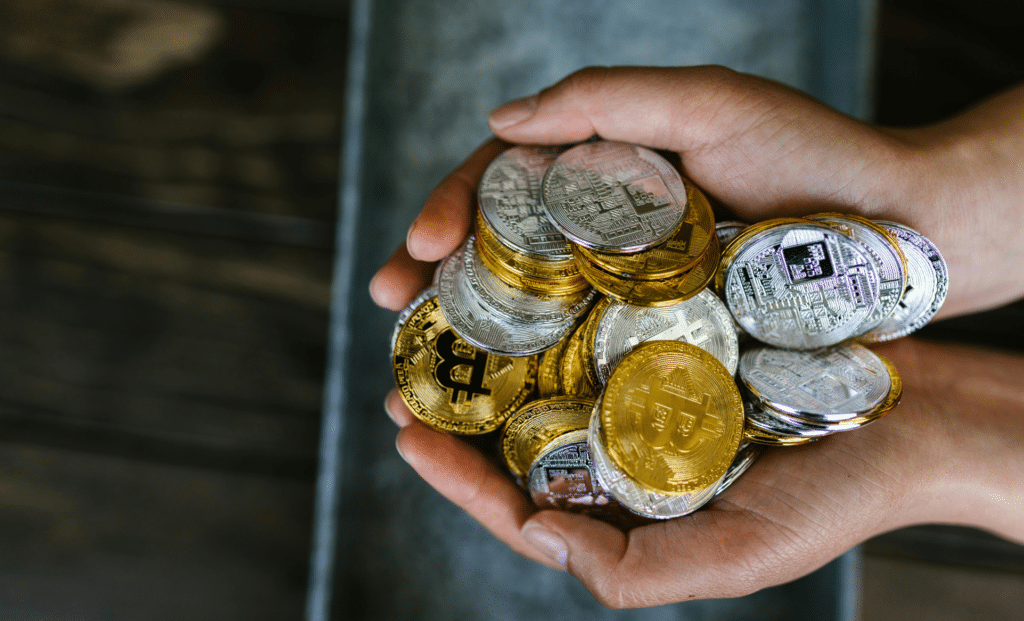 Hands holding physical crypto coins representing a utility token used in a utility token white paper MiCA context for token issuance and regulatory compliance